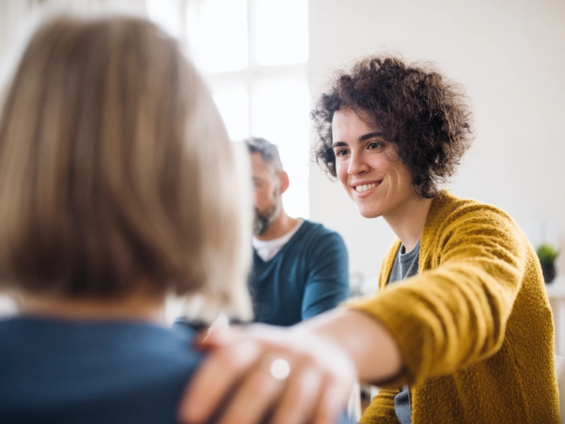 Woman with curly hair providing support in a group counselling session